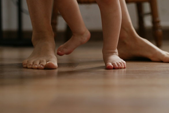 a close up of a child's bare feet on a wooden floor